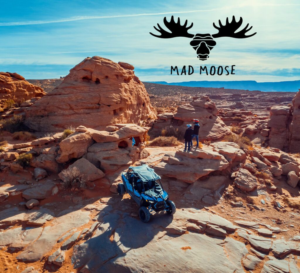 A breathtaking desert landscape near Settlers Point RV Park in Utah, showcasing rugged red rock formations, an ATV, and adventurers exploring the scenic terrain.