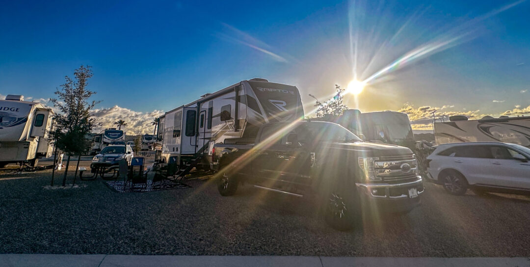 Sunsrise over Settlers Point RV Park in Utah, showcasing modern RVs, a Raptor fifth-wheel, and spacious sites in a scenic campground setting.