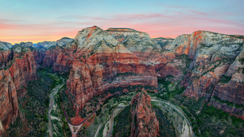 Breathtaking aerial view of Zion National Park's red rock canyon formations with winding river during golden hour sunrise