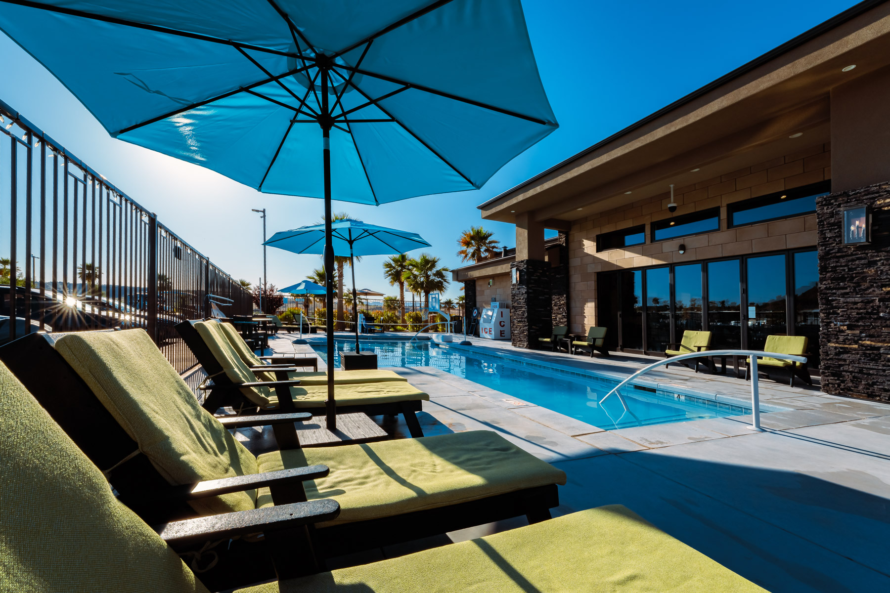 Poolside loungers and umbrellas beside the clubhouse at a luxury rv resort, supporting luxury rv resorts in utah and rv camping St George Utah.