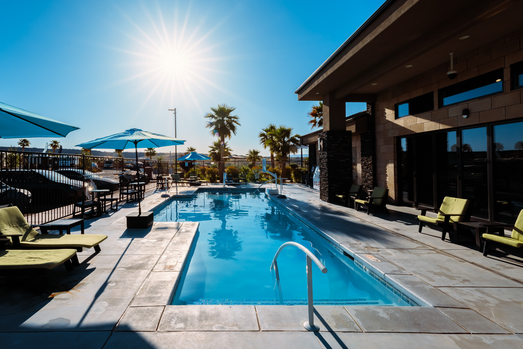 Pool with loungers and umbrellas beside the clubhouse at a luxury rv resort in St George Utah, a standout rv parks amenity.