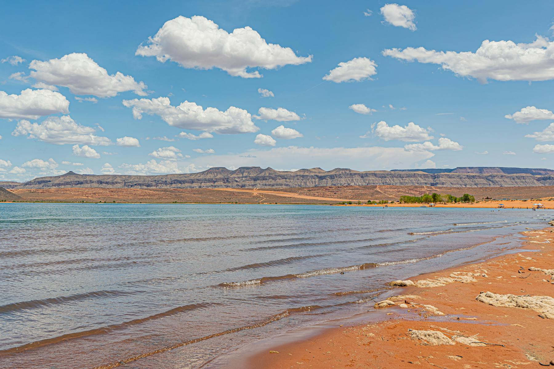 Red sand shoreline along Sand Hollow State Park reservoir with desert cliffs and blue sky in southern Utah. Photo by Castorly Stock https://www.pexels.com/@castorlystock