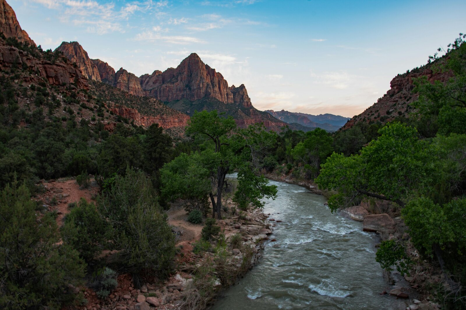 Majestic rocky mountains rising in the distance, with a winding river flowing through a lush, green valley below.
